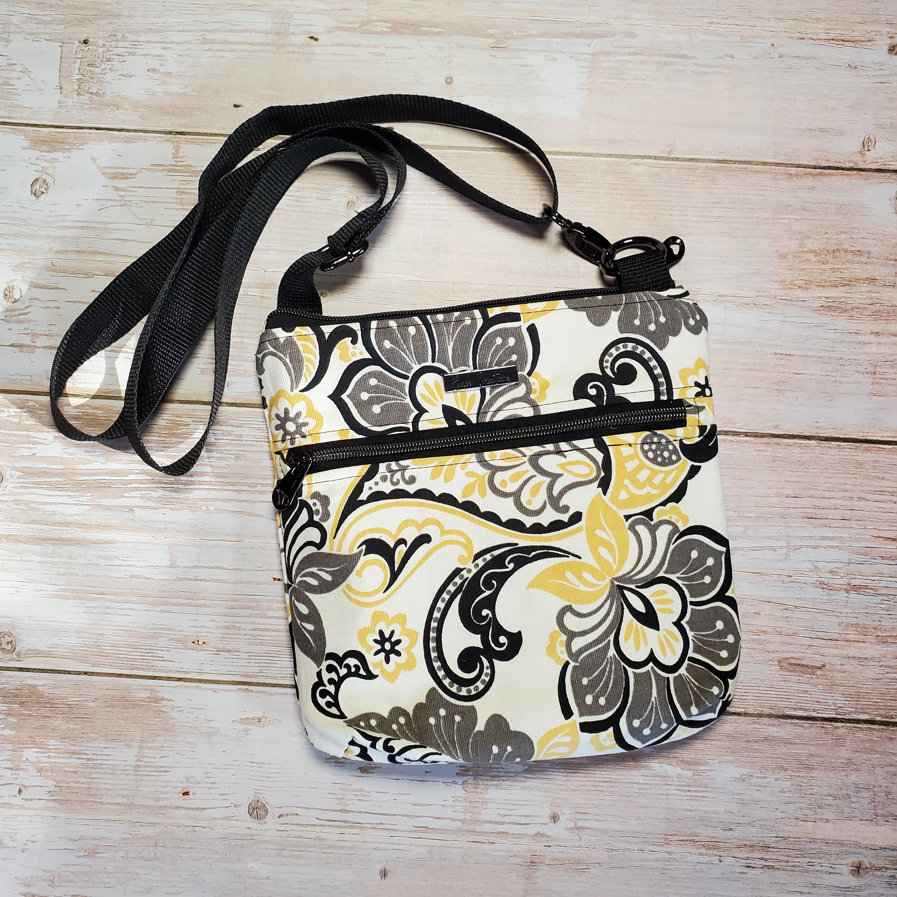 Top view of a yellow, gray and black medium crossbody with gunmetal zippers and a gunmetal Bass Creations logo.