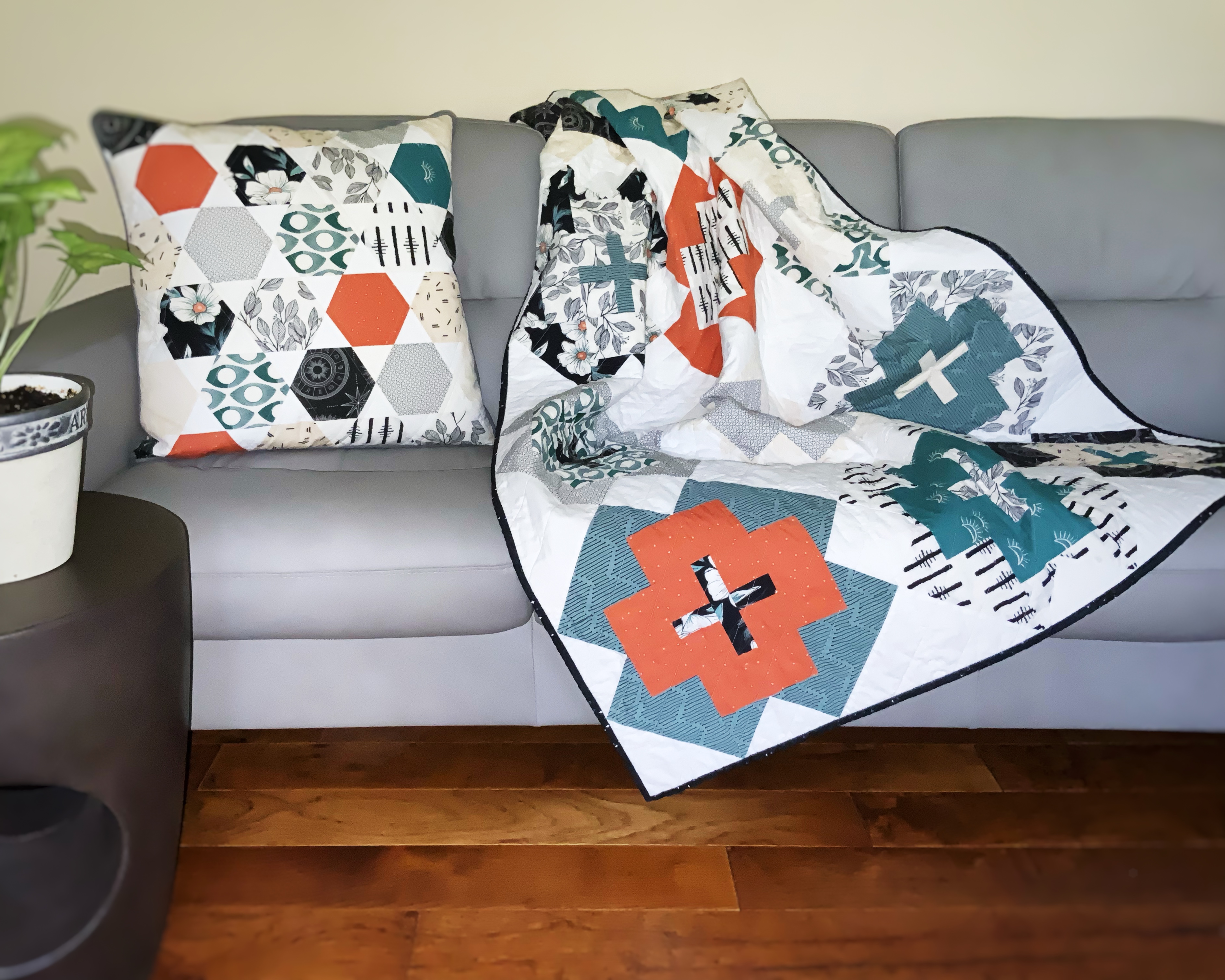 Handmade quilt, 44 X 58, various modern print fabrics in teal, burnt orange, black and ivory on white, floral backing; comes with 20" matching pillow