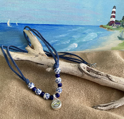 White Ceramic beads with blue flowers on a silver trill key that is actually now a pendant.  This is a  stunning lightweight necklace and there are only two in  the world. Simplistic but  lovely and will be admired by all who see it.